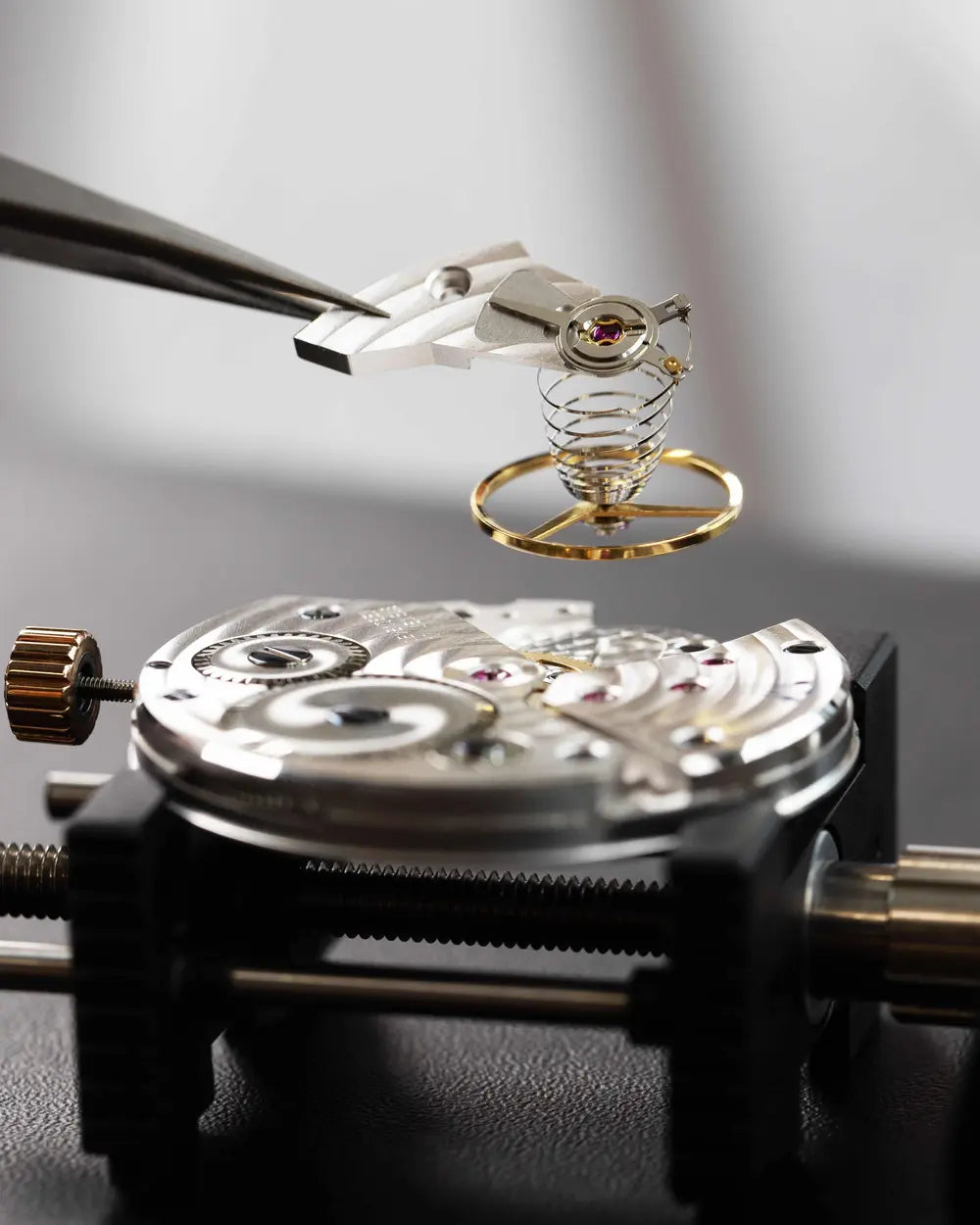 Watchmaker placing a balance wheel and escapement onto a Swiss ETA Unitas 6497 movement during assembly at Watch Academy by Cimier